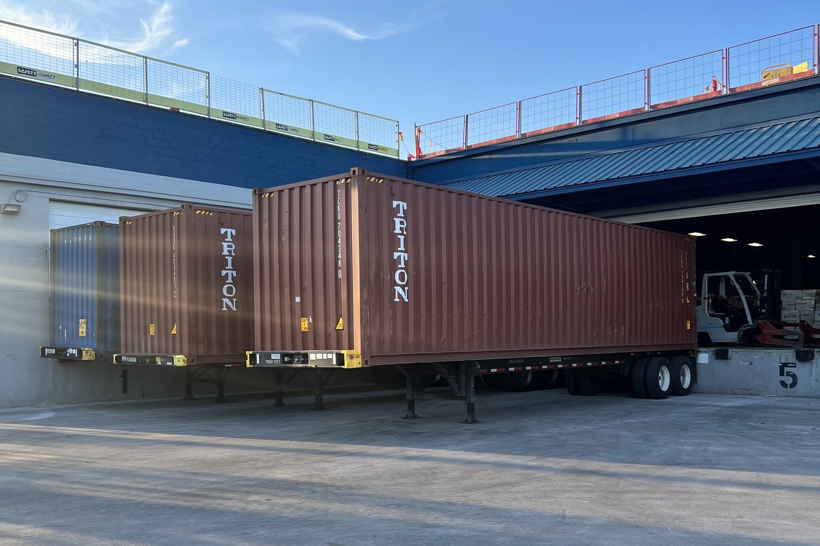 Shipping containers on chassis being loaded with used clothing bales at US Dynamics in Houston